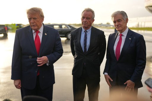 President Donald Trump talks with reporters after arriving on Air Force One, Friday, Oct. 23, 2026, at President Donald J. Trump International Airport in West Palm Beach, Fla., as Health and Human Services Secretary Robert F. Kennedy Jr. and Centers for Medicare & Medicaid Services administrator Dr. Mehmet Oz listen. (AP Photo/Mark Schiefelbein)