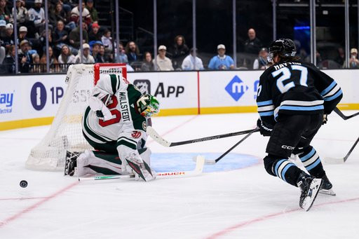 Minnesota Wild goaltender Jesper Wallstedt (30) makes the behind the back save on a shot from Utah Mammoth center Barrett Hayton (27) during the second period of an NHL hockey game Tuesday, Oct. 27, 2026, in Salt Lake City. (AP Photo/Tyler Tate)