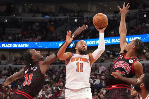 New York Knicks guard Jalen Brunson, center, shoots the ball on Chicago Bulls forward Leonard Miller, left, and guard Norman Powell, right, during the first half of an NBA basketball game, Wednesday, Oct. 28, 2026, in Chicago. (AP Photo/David Banks)