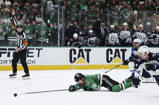 Dallas Stars center Sam Steel (18) is tripped by Winnipeg Jets' Mark Scheifele, right rear, on an attack in the third period of Game 6 of a second-round NHL hockey playoff series in Dallas, Saturday, May 17, 2025. (AP Photo/Gareth Patterson)
