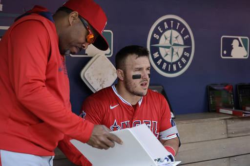 Los Angeles Angels' Mike Trout talks with batting coach Johnny Washington in the dugout before a baseball game against the Seattle Mariners, Wednesday, April 30, 2025, in Seattle. (AP Photo/John Froschauer)