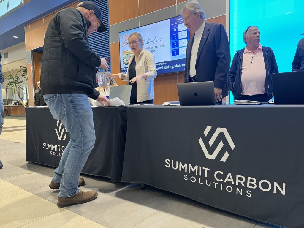 Representatives with Summit Carbon Solutions hand out information and answer questions ahead of a Public Utilities Commission hearing in Sioux Falls on Jan. 15, 2025. (Makenzie Huber/South Dakota Searchlight)