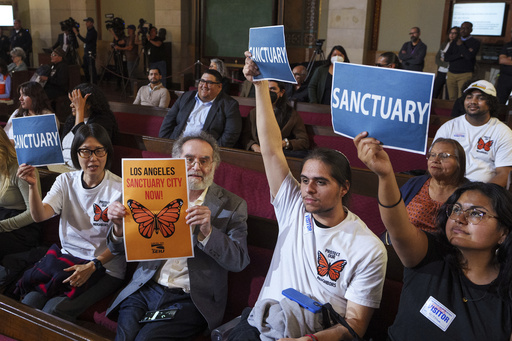 FILE - Members of immigration advocacy groups react as Los Angeles City Council votes to enact an ordinance to prohibit city resources from being used for immigration enforcement in anticipation of potential mass deportations under President-elect Donald Trump, inside Los Angeles City Hall on Tuesday, Nov. 19, 2024. (AP Photo/Damian Dovarganes, File)