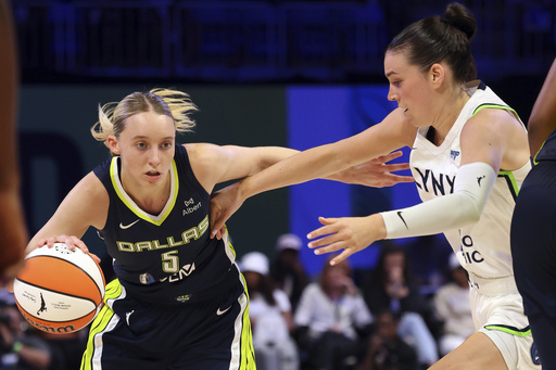 Dallas Wings guard Paige Bueckers (5) drives the ball past Minnesota Lynx forward Bridget Carleton, right, in the first half in a WNBA basketball game Friday, May 16, 2025, in Arlington, Texas. (AP Photo/Richard W. Rodriguez)
