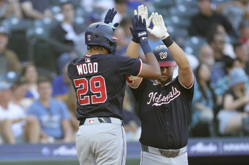 Washington Nationals' James Wood high fives Nathaniel Lowe after hitting a solo home run during the fifth inning of a baseball game against the Seattle Mariners Wednesday, May 28, 2025, in Seattle. (AP Photo/Ryan Sun)