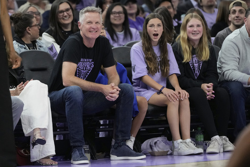 Golden State Warriors head coach Steve Kerr, foreground left, smiles during the second half of a WNBA basketball game between the Golden State Valkyries and the Los Angeles Sparks in San Francisco, Friday, May 16, 2025. (AP Photo/Jeff Chiu)