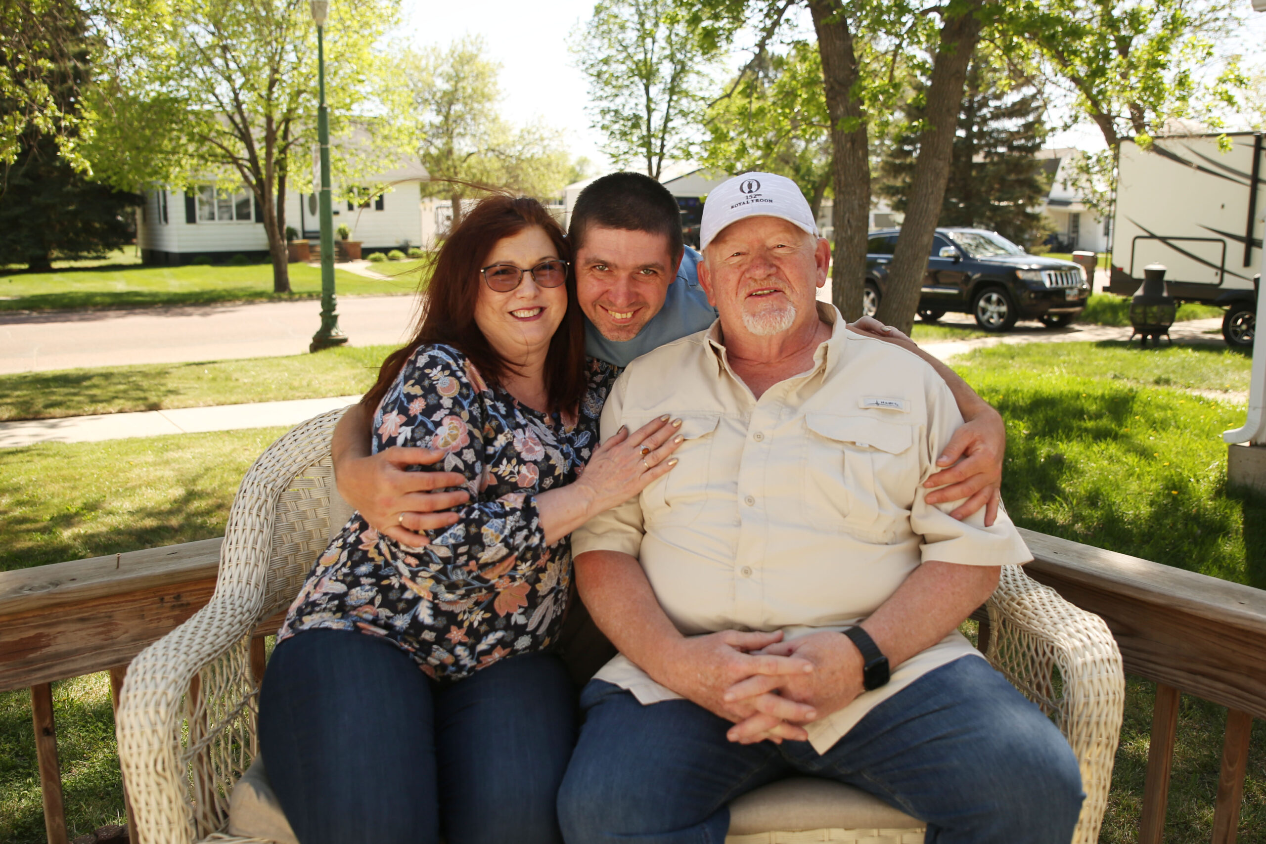(Left to right) Susan Buhler, Valerii Biliaze and Bruce Buhler pose for a photo out side of Biliaze's house in Watertown on May 12, 2025. (Makenzie Huber/South Dakota Searchlight)