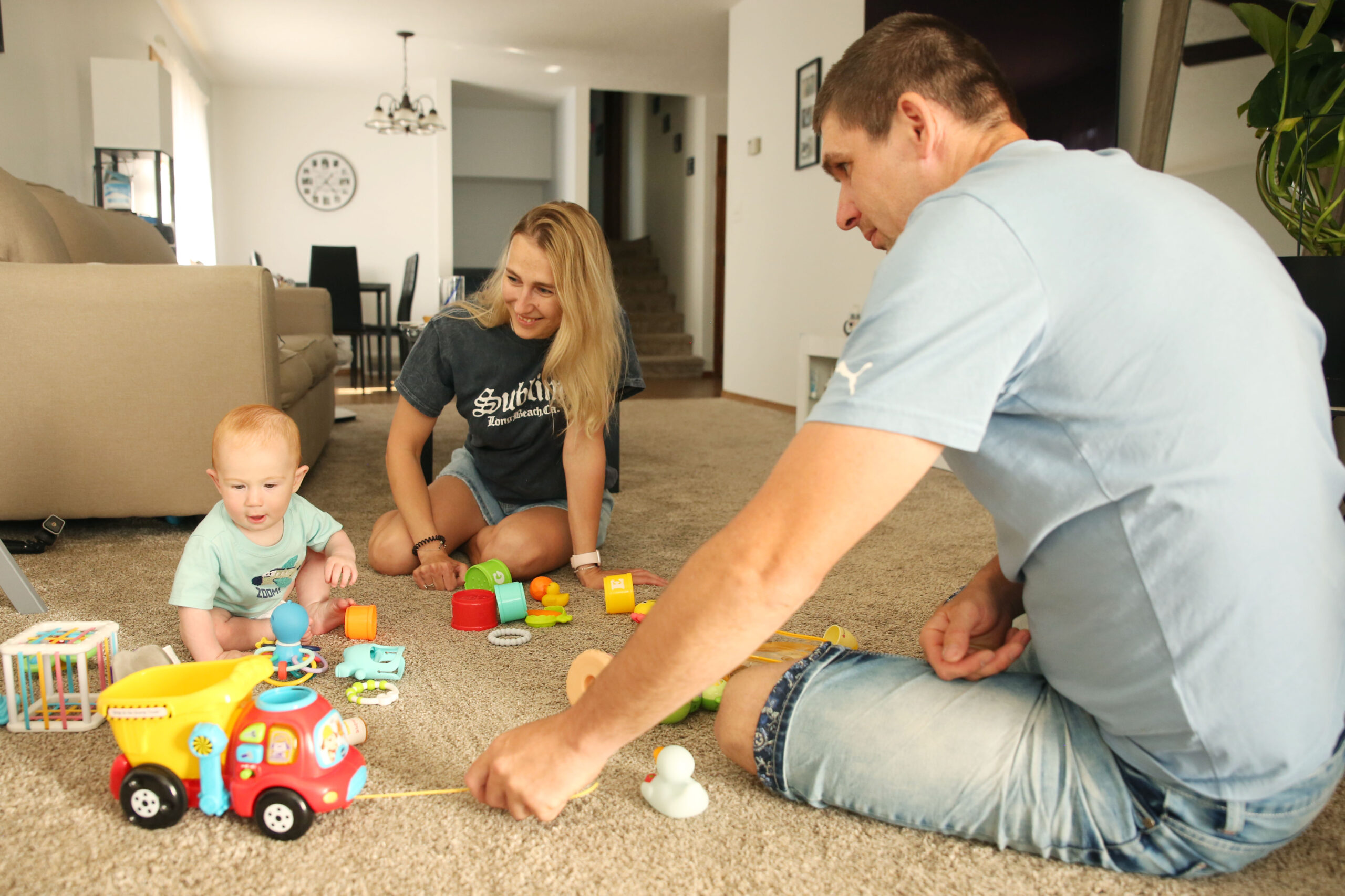 Ilona and Valerii Biliaze play with their 7-month-old son Brian in their Watertown home on May 12, 2025. (Makenzie Huber/South Dakota Searchlight)