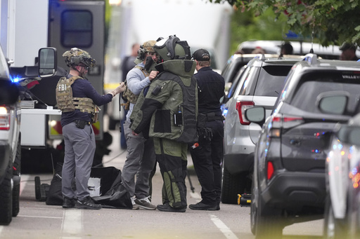 Law enforcement officials dress up in protective gear to investigative an attack on the Pearl Street Mall, Sunday, June 1, 2025, in Boulder, Colo. (AP Photo/David Zalubowski)