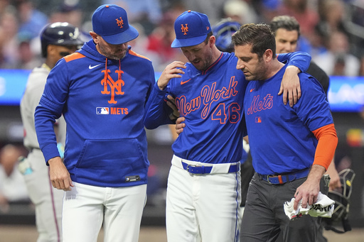 New York Mets pitcher Griffin Canning, center, is helped off the field by head athletic trainer Joseph Golia, right, and pitching coach Jeremy Hefner during the third inning of a baseball game against the Atlanta Braves Thursday, June 26, 2025, in New York. (AP Photo/Frank Franklin II)