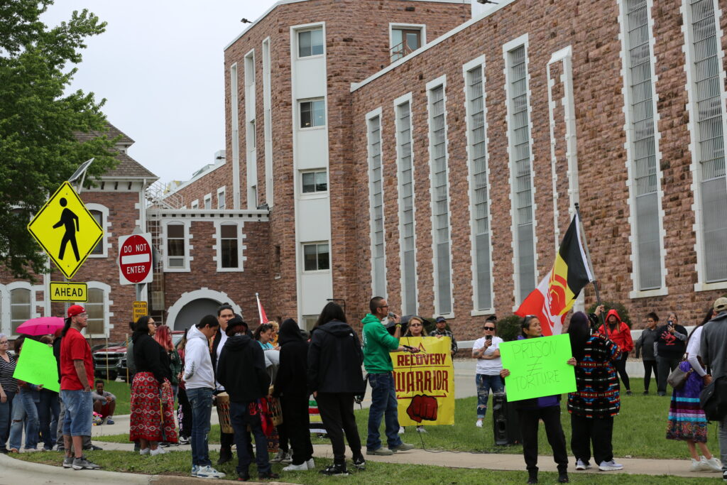 People hold signs at a protest on May 23, 2025, at the South Dakota State Penitentiary in Sioux Falls. (John Hult/South Dakota Searchlight)