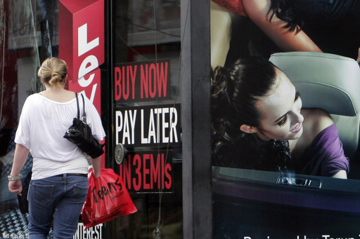 FILE - A woman walks by a sign "Buy now pay later" at a store in Bangalore, India, on Sept. 10, 2009. (AP Photo/Aijaz Rahi, File)