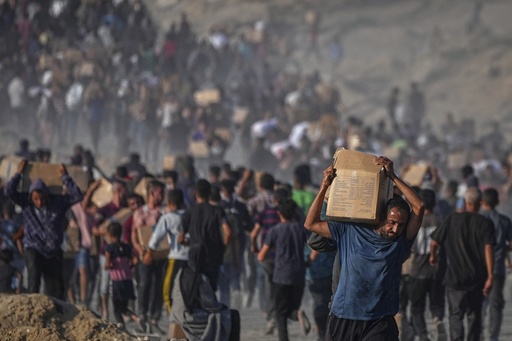Palestinians carry sacks and boxes of food and humanitarian aid unloaded from a World Food Program convoy that had been heading to Gaza City, in the northern Gaza Strip, Monday, June 16, 2025. (AP Photo/Jehad Alshrafi)