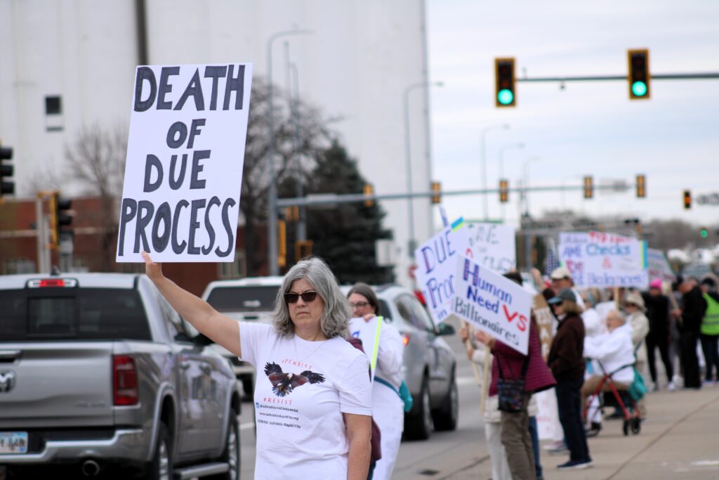 Nicole Preble holds a sign during a protest against the Trump administration on April 23, 2025, in Rapid City. (Seth Tupper/South Dakota Searchlight)
