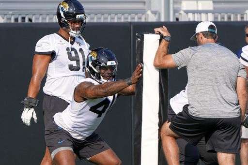 Jacksonville Jaguars defensive end Josh Hines-Allen, center, performs a drill as defensive end Arik Armstead (91) looks on during a team NFL football practice, Monday, June 2, 2025, in Jacksonville, Fla. (AP Photo/John Raoux)