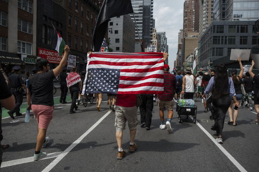 Protester carries an upside down American flag during a protest against U.S. strikes on Iran, Sunday, June 22, 2025, in New York. (AP Photo/Olga Fedorova)
