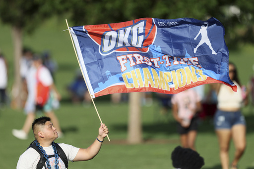 A fan holds a flag before a celebration of the Oklahoma City Thunder's NBA basketball championship Tuesday, June 24, 2025, in Oklahoma City. (AP Photo/Nate Billings)