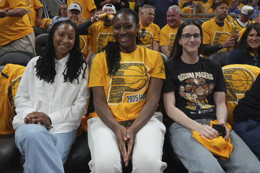 Indian Fever basketball players Caitlin Clark, right, and Aliyah Boston, center, watch during the first half of Game 4 of the NBA Finals basketball series between the Indiana Pacers and the Oklahoma City Thunder, Friday, June 13, 2025, in Indianapolis. (AP Photo/Michael Conroy)