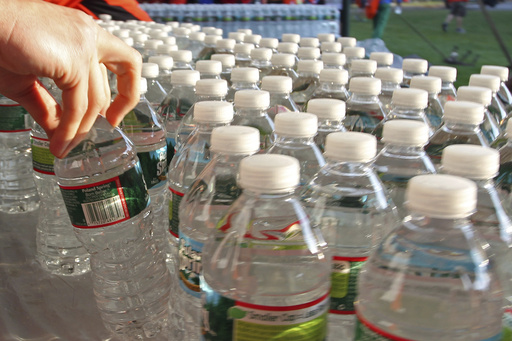 FILE - A runner grabs a bottle of water at the athlete's village prior to the start of the 116th running of the Boston Marathon, in Hopkinton, Mass., April 16, 2012. (AP Photo/Stew Milne, File)