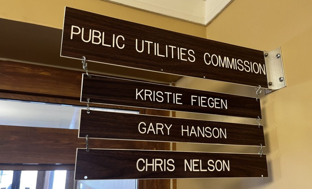 A sign displays the names of South Dakota's three elected public utilities commissioners outside of their Pierre office in January 2023. (Joshua Haiar/South Dakota Searchlight)