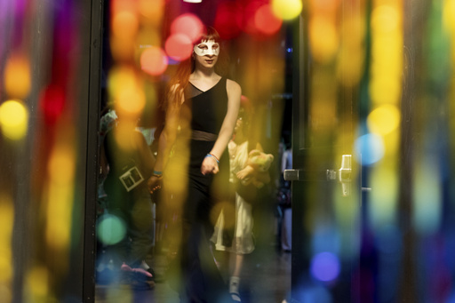 Melody Jenkins is seen through rainbow streamers during a "Pink Pony Prom" organized by the Sexual & Gender Minority Youth Resource Center, part of New Avenues for Youth, a nonprofit dedicated to ending youth homelessness, on Friday, May 30, 2025, in Portland, Ore. (AP Photo/Jenny Kane)