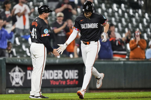 Baltimore Orioles' Coby Mayo, right, celebrates with interim third base/infield coach Buck Britton (46) after hitting a two-run home run during the eighth inning of a baseball game against the Tampa Bay Rays, Friday, June 27, 2025, in Baltimore. (AP Photo/Stephanie Scarbrough)