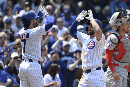 Chicago Cubs' Michael Busch, right, high fives Dansby Swanson after they score on Busch's two-run home run during the third inning of a baseball game against the Cincinnati Reds, Sunday, June 1, 2025, in Chicago. (AP Photo/Matt Marton)