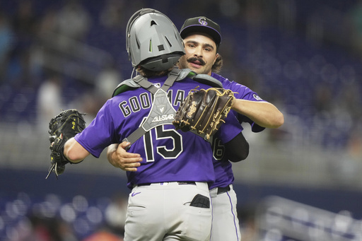 Colorado Rockies relief pitcher Zach Agnos, right, embraces catcher Hunter Goodman (15) after the Rockies defeated the Miami Marlins in a baseball game, Monday, June 2, 2025, in Miami. (AP Photo/Lynne Sladky)