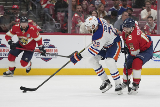 Edmonton Oilers center Leon Draisaitl (29) takes control of the puck as Florida Panthers left wing Matthew Tkachuk (19) defends during the third period of Game 4 of the NHL hockey Stanley Cup Final Thursday, June 12, 2025, in Sunrise, Fla. (AP Photo/Lynne Sladky)