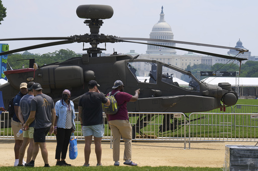 People look at a military helicopter with the Capitol in the background, Friday, June 13, 2025, on the National Mall in Washington, during preparations for an upcoming military parade commemorating the Army's 250th anniversary and coinciding with President Donald Trump's 79th birthday. (AP Photo/Jacquelyn Martin)