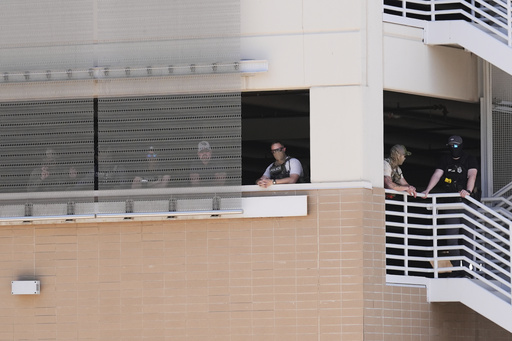 FILE - Federal law enforcement wait in a parking garage to take people into custody outside immigration court, May 21, 2025, in Phoenix. (AP Photo/Ross D. Franklin, File)