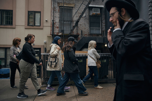 Tour participants walk past an ultra-Orthodox Jewish man during a tour by Frieda Vizel of the Hasidic section of Williamsburg in the Brooklyn borough of New York on Monday, June 16, 2025. (AP Photo/Andres Kudacki)