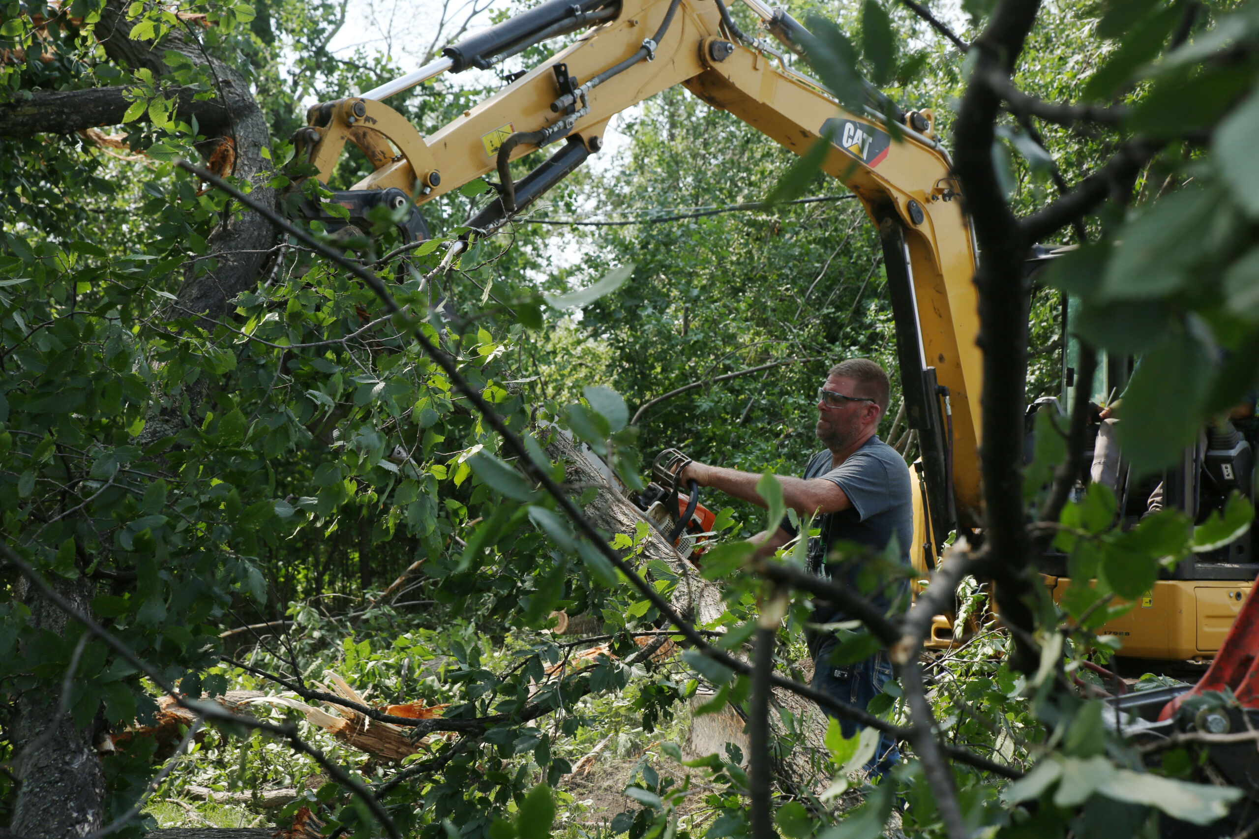 Hudson resident Doug Klarenbeek helps clean up tree debris in the town on Tuesday, July 29, 2025 after severe weather moved through the area Monday evening. The system damaged trees, homes and other structures. (Makenzie Huber/South Dakota Searchlight)