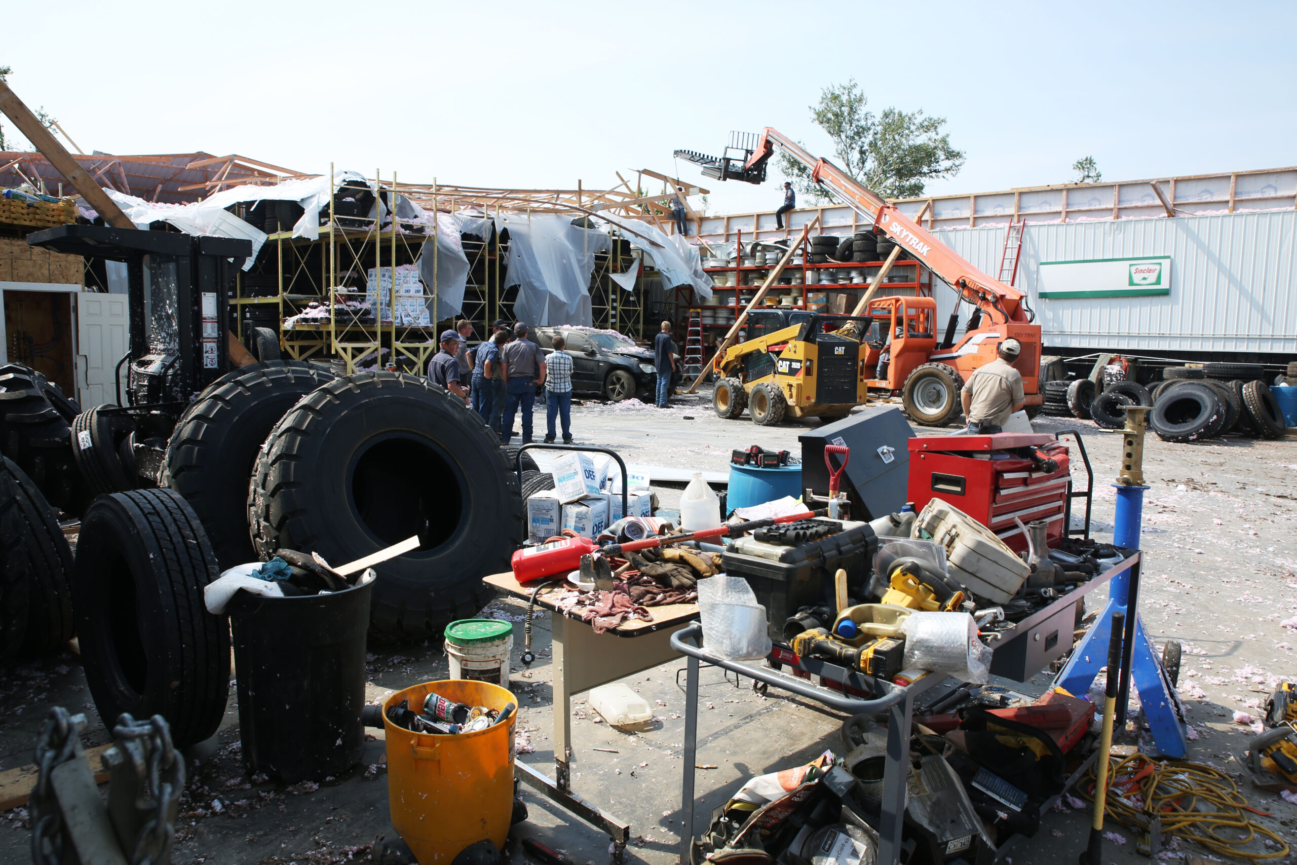 Volunteers help clean up damaged warehouse in Hudson on Tuesday, July 29, 2025 after severe weather blew the roof off of the building Monday evening. The system damaged trees, homes and other structures. (Makenzie Huber/South Dakota Searchlight)