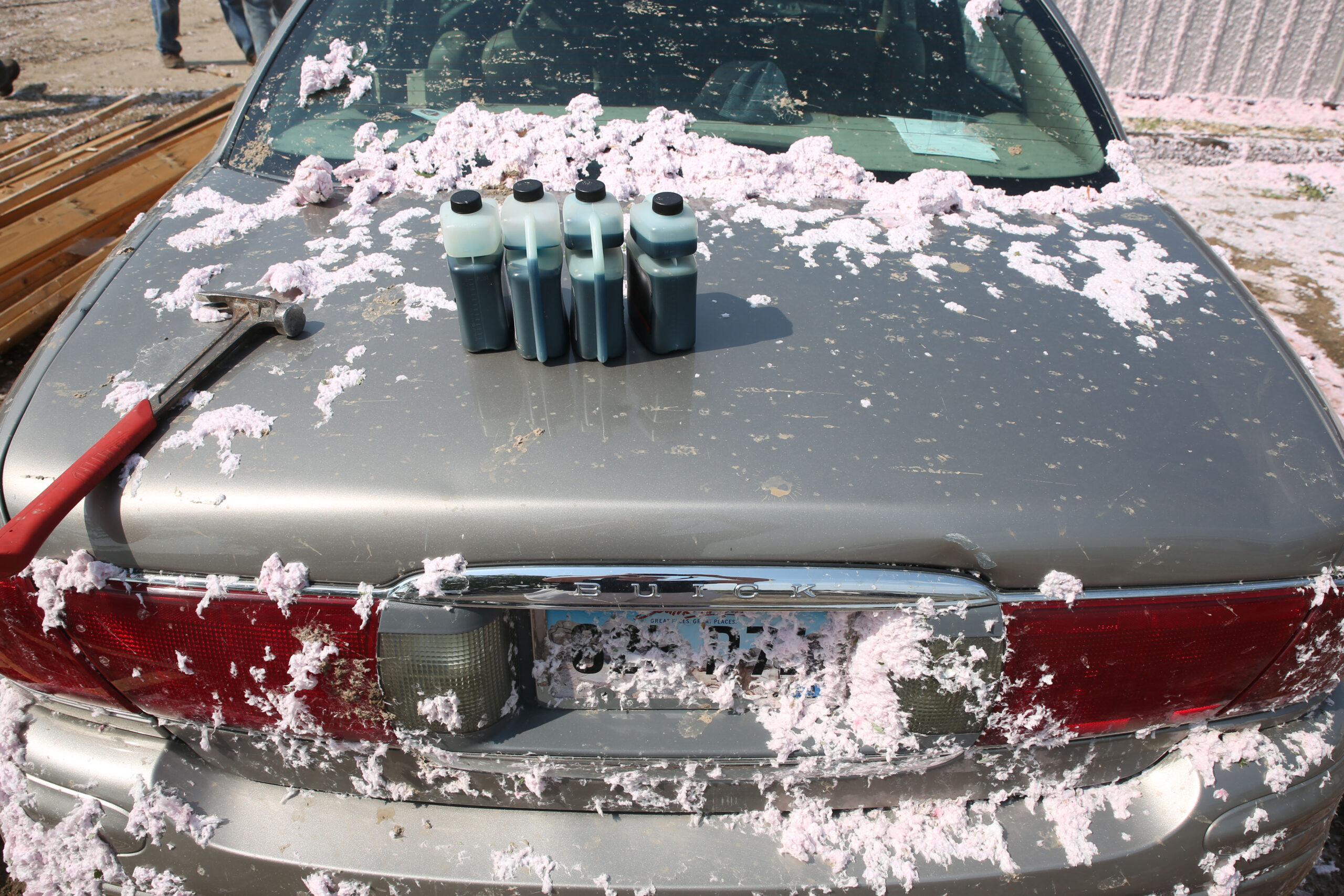 Fiber glass insulation covers cars, buildings and grass on Tuesday, July 29, 2025 after a warehouse roof was blown off by a wind storm that moved through the area on Monday evening. The system damaged trees, homes and other structures. (Makenzie Huber/South Dakota Searchlight)