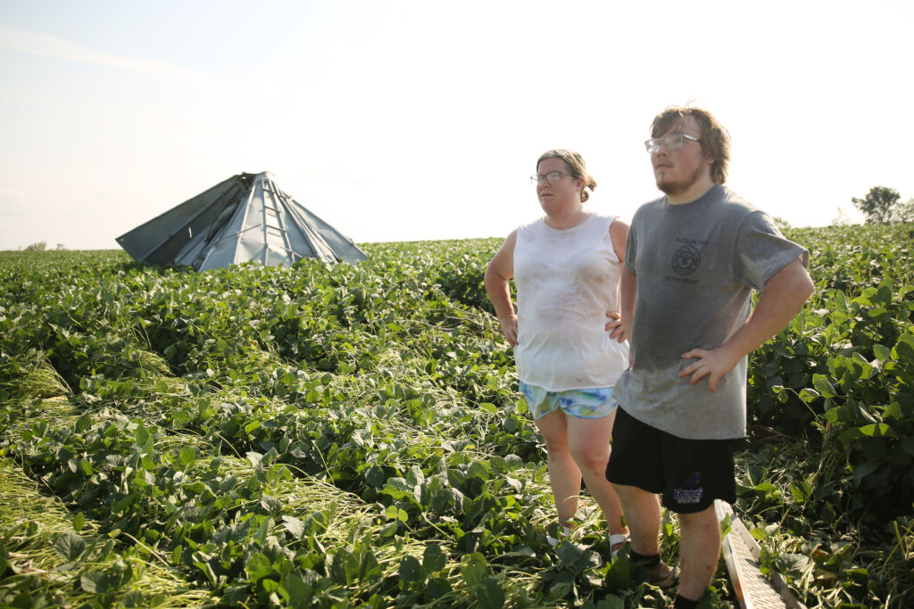 Amanda Lounsbery (left) and her son Hayden Lounsbery survey damage to their family's soybean fields on July 29, 2025. Their grain bin carved a path into the field and split into two pieces after a storm system moved through the area the previous evening. The system damaged trees, homes and other structures. (Makenzie Huber/South Dakota Searchlight)
