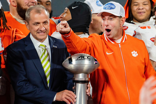 Clemson head coach Dabo Swinney, with ACC commissioner Atlantic Coast Conference Commissioner Jim Phillips by his sides, looks on after winning the ACC championship NCAA college football game between Clemson and SMU, Saturday, Dec. 7, 2024, in Charlotte, N.C. (AP Photo/Jacob Kupferman, File)