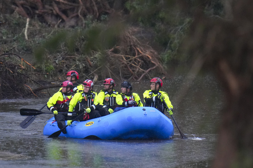 Officials ride a boat as they arrive to assist with a recovery effort at Camp Mystic along the Guadalupe River, Sunday, July 6, 2025, in Hunt, Texas, after a flash flood swept through the area. (AP Photo/Julio Cortez)