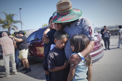 People embrace outside of Glass House Farms, a day after an immigration raid on the facility, on Friday, July 11, 2025, in Camarillo, Calif. (AP Photo/Damian Dovarganes)