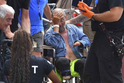 Michael Pimentel, center, a resident at the Gabriel House assisted living facility, in Fall River, Mass., receives assistance from an emergency medical worker, right, outside a temporary shelter, Monday, July 14, 2025, in Fall River, following a fire that started late Sunday. (AP Photo/Steven Senne)