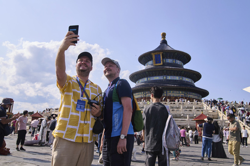 Tourists take a selfie at the Temple of Heaven as they take a half-day tour offering by a travel agency Trip.com Group, in Beijing on June 15, 2025. (AP Photo/Andy Wong)