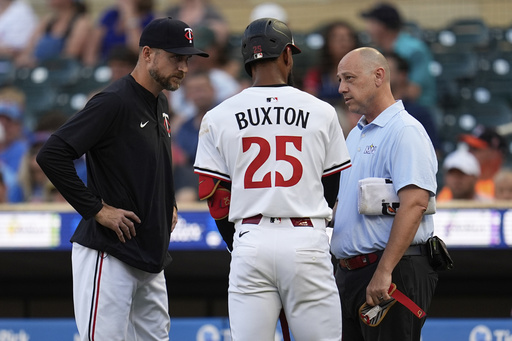 Minnesota Twins' Byron Buxton (25) is looked at by manager Rocco Baldelli (5), left, and a trainer after being hit by a pitch during the first inning of a baseball game against the Chicago Cubs Wednesday, July 9, 2025, in Minneapolis. (AP Photo/Abbie Parr)