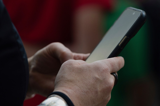 FILE - A person looks at their phone at Seattle–Tacoma International Airport on Sunday, June 1, 2025, in Seattle. (AP Photo/Jenny Kane, File)