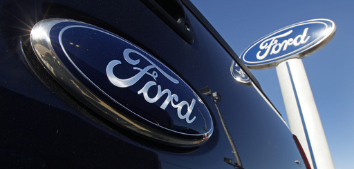 FILE - A Ford logo is on the tailgate of a pick-up truck and on a Ford dealership sign in Salem, N.H. (AP Photo/Charles Krupa, File)