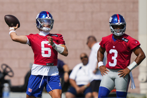 New York Giants quarterback Jaxson Dart (6) throws as quarterback Russell Wilson (3) watches during practice at the team's NFL football training camp in East Rutherford, N.J., Wednesday, July 23, 2025. (AP Photo/Yuki Iwamura)