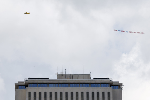 An airplane towing a banner that reads "Trump and Bondi are protecting predators" is seen over the Florida Capitol, Friday, July 25, 2025, in Tallahassee, Fla., as Deputy Attorney General Todd Blanche meets with Ghislaine Maxwell, the imprisoned former girlfriend of financier and convicted sex offender Jeffrey Epstein in the nearby federal courthouse. (AP Photo/Colin Hackley)