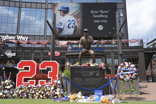 Fans leave flowers and other items at a makeshift memorial in front of the statue of Chicago Cubs' Hall of Fame second baseman Ryne Sandberg, Tuesday, July 29, 2025, outside Wrigley Field in Chicago. (AP Photo/Nam Y. Huh)