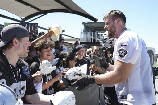 Las Vegas Raiders offensive tackle Kolton Miller, right, gives autographs after the team's NFL football training camp, Sunday, July 27, 2025, in Henderson, Nev. (AP Photo/Candice Ward)