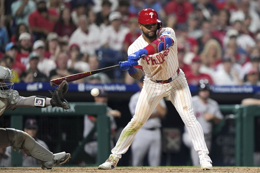 Philadelphia Phillies' Edmundo Sosa, right, hits the glove of Boston Red Sox catcher Carlos Narváez for catcher's interference with the bases loaded in the 10th inning of a baseball game Monday, July 21, 2025, in Philadelphia. (AP Photo/Matt Slocum)