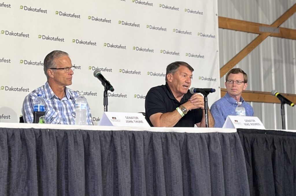 From left, U.S. Sen. John Thune, U.S. Sen. Mike Rounds and U.S. Rep. Dusty Johnson, all Republicans of South Dakota, talk about agriculture policy at Dakotafest in Mitchell on Aug. 21, 2024. (Joshua Haiar/South Dakota Searchlight)
